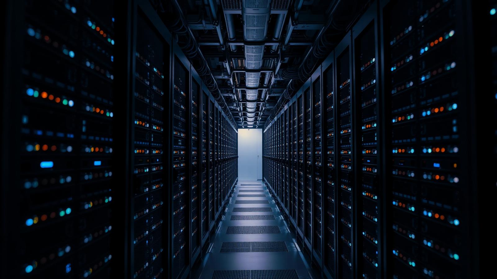 Rows of GPU server racks glowing in a dark data centre aisle